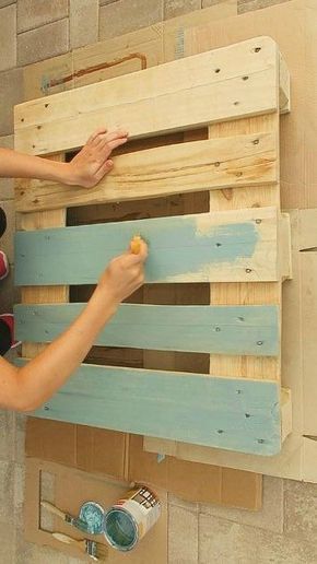 a woman is painting the side of a wooden pallet