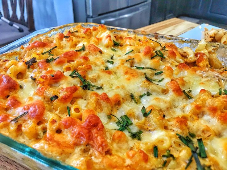 a casserole dish with cheese, tomatoes and spinach in it on a wooden table