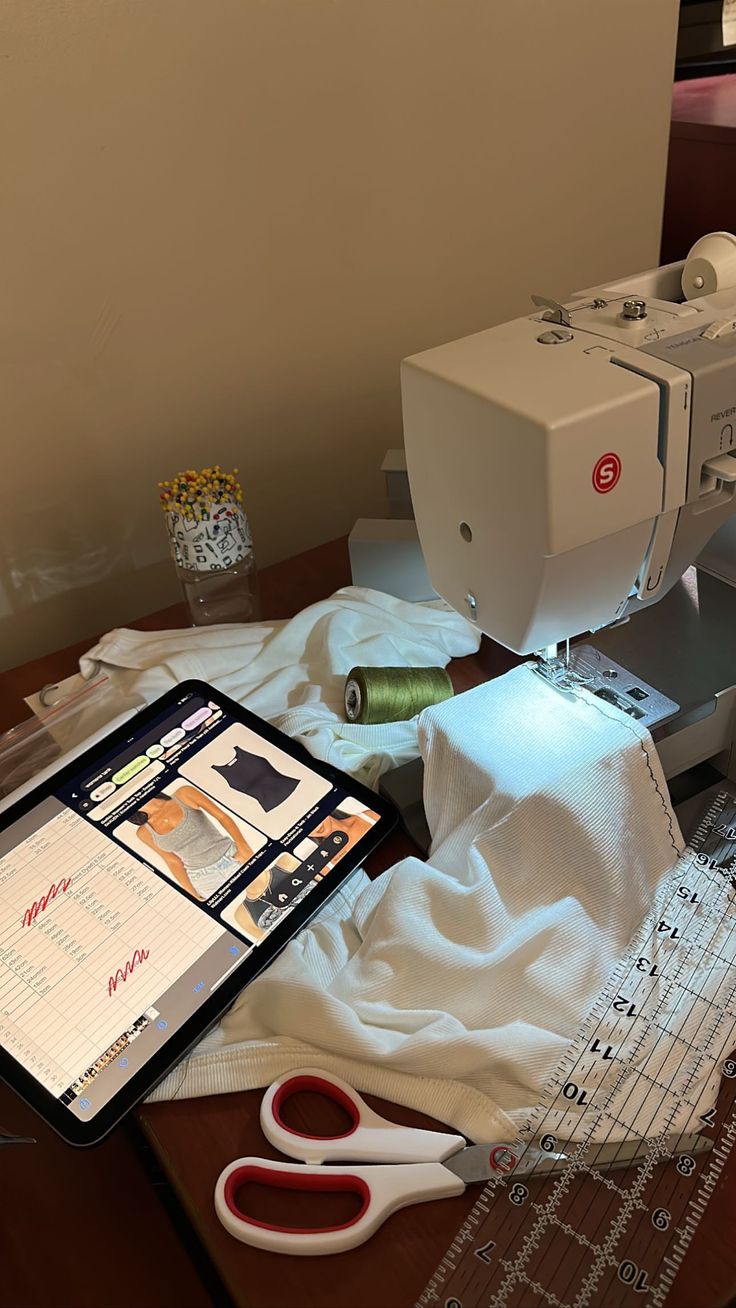 a sewing machine sitting on top of a wooden table next to scissors and threading