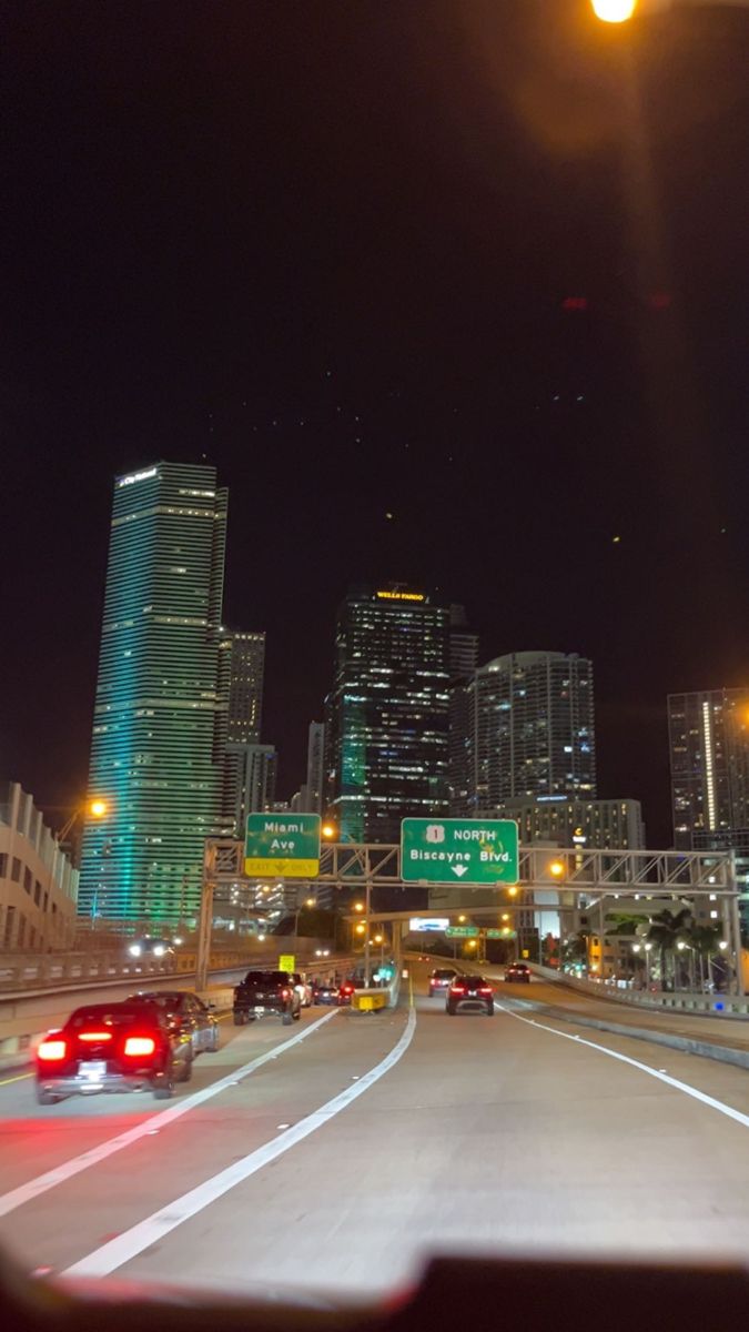 cars driving down the highway at night with skyscrapers in the background