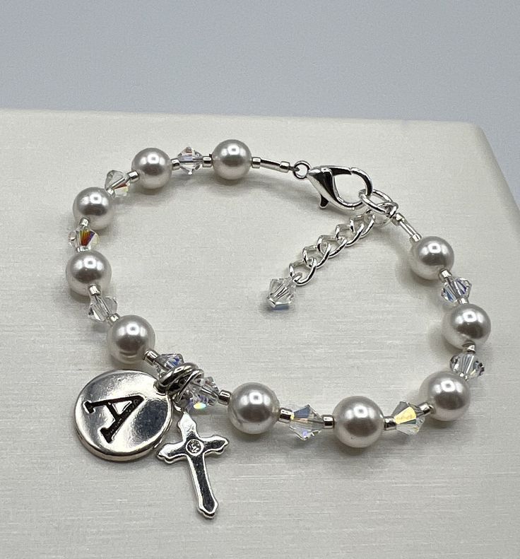 "This stunning bracelet is designed using 6mm white exquisite crystal pearls, 4mm AB Austrian Crystal, a pewter initial charm and a sterling silver cross with a cubic zirconia in the center!  This piece is finished with a sterling silver plated lobster clasp and soldered jump ring. A 1\" extender chain with a 4mm crystal dangle adds to this special piece. A wonderful keepsake for a Communion or Confirmation. If you don't see the size you need please let me know!" Classic Silver Rosary Bracelet As Gift, Elegant Personalized Jewelry For Confirmation, Silver Pearl Bracelets With 8mm Beads, Silver Rosary Bracelet With Round Beads For First Communion, Elegant Silver Charm Bracelet With 8mm Beads, Silver Jewelry With 8mm Beads For First Communion, Elegant Silver Name Bracelet With Round Beads, Silver Pearl Bracelet With 8mm Beads For Gift, Silver Pearl Bracelet With 8mm Beads As Gift