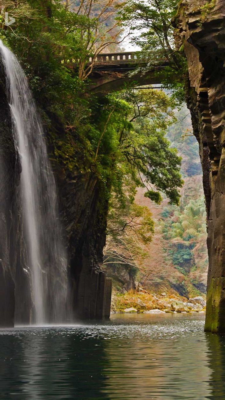 a large waterfall with a bridge over it