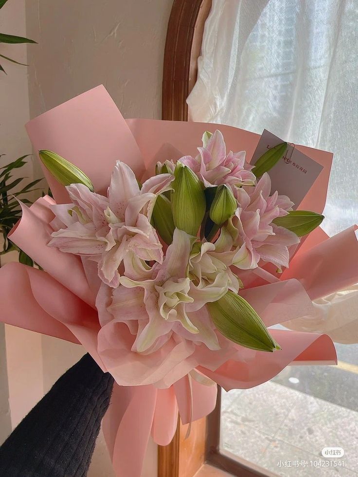 a bouquet of pink and white flowers in front of a mirror