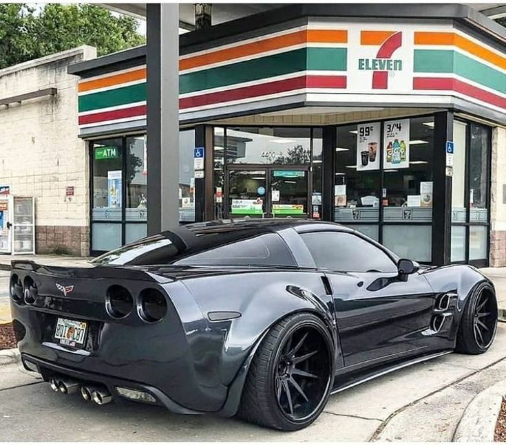 a black sports car parked in front of a gas station