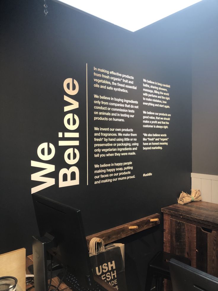 a black wall with white writing on it in an office space next to a desk and chair