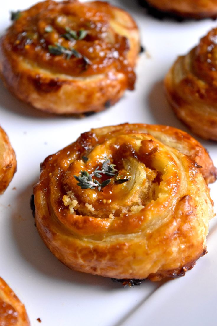 several small pastries on a white plate with some green sprigs in the middle