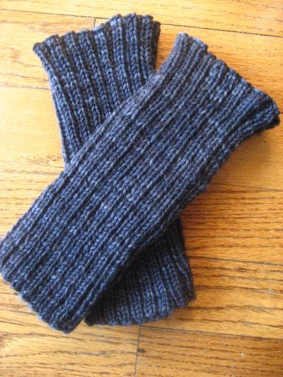 two gray knitted gloves sitting on top of a wooden floor