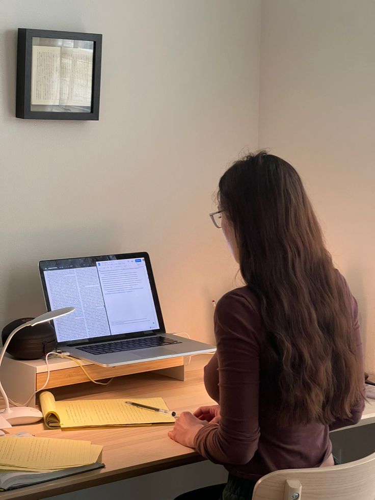 a woman sitting at a desk with a laptop computer