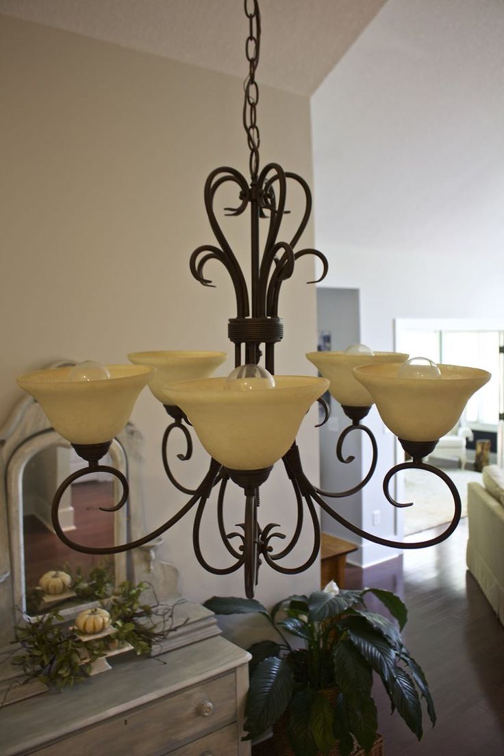 a chandelier hanging from a ceiling in a living room next to a potted plant