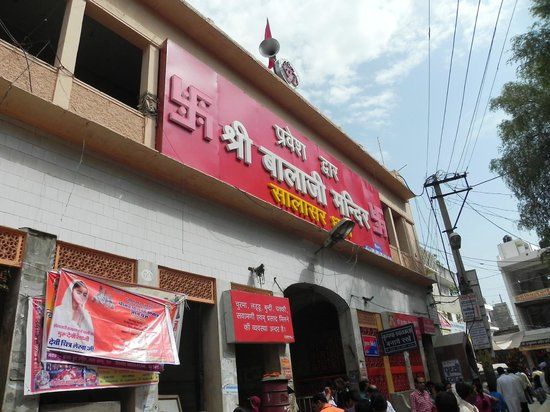 people walking in front of a building with red and white signage on it's side