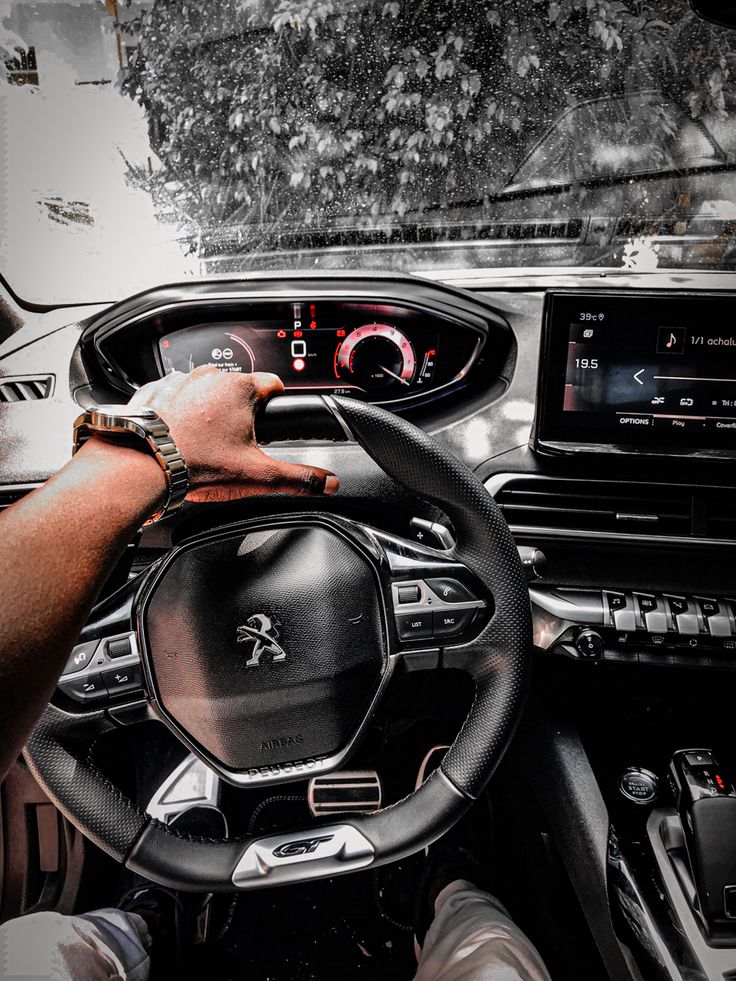 a man driving a car with the steering wheel and dash light on, in front of him