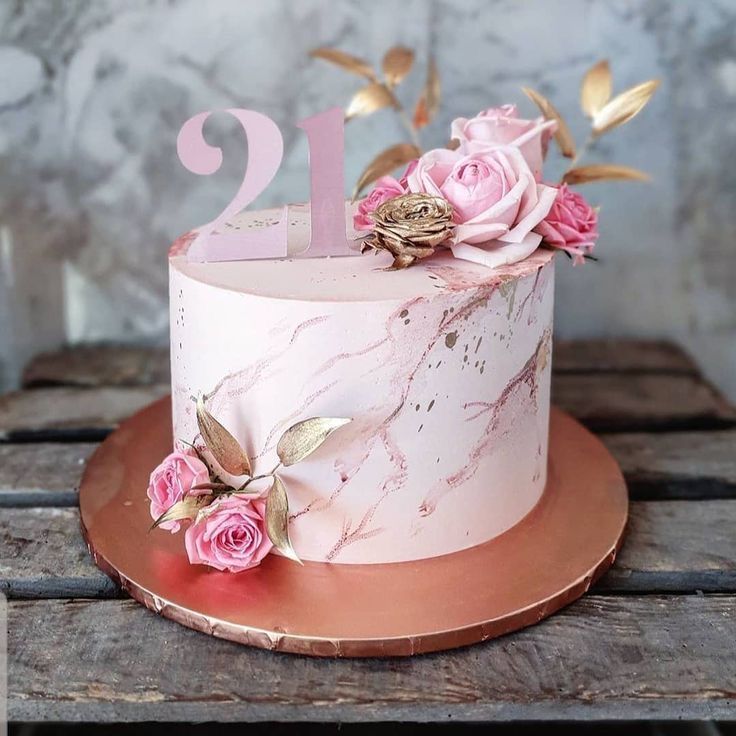 a pink marbled cake with flowers and the number one on top is sitting on a wooden table