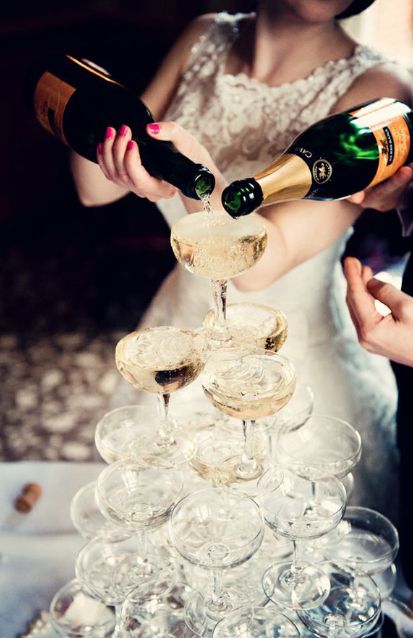 the bride and groom are pouring champagne into wine glasses on top of each other at their wedding reception