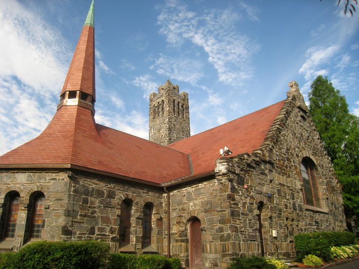 an old stone church with a red roof and steeple