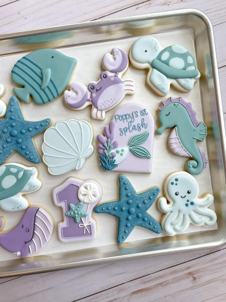 there are many decorated cookies in the tray on the table, including sea animals and seashells