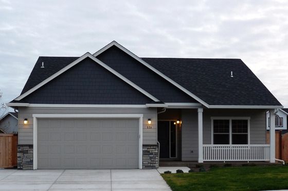 a gray house with two garages in the front and one on the other side