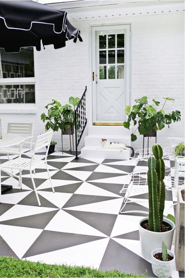 an outdoor patio with potted plants on the floor and a black and white checkerboard design