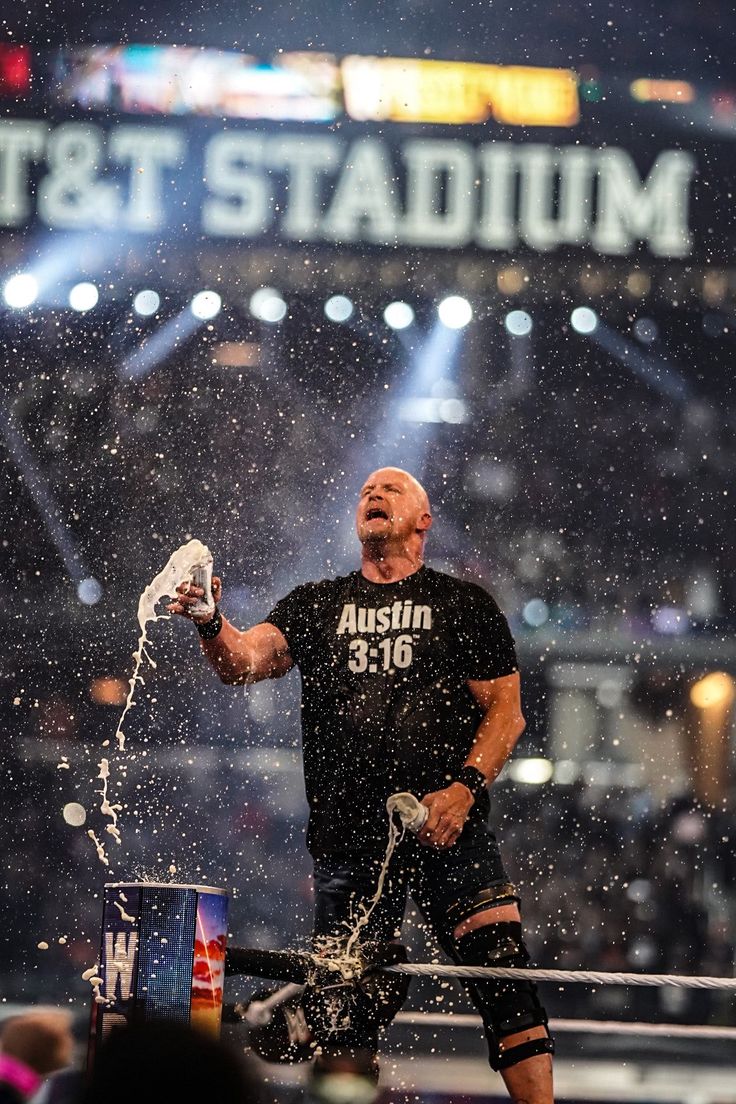 a man in black shirt standing on top of a wrestling ring with water pouring from his hands