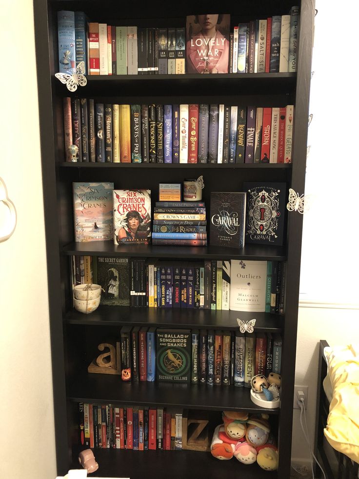 a bookshelf filled with lots of books next to a wall mounted toilet in a bathroom