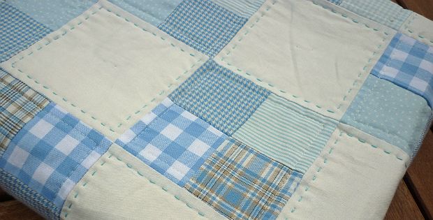 a blue and white patchwork quilt sitting on top of a wooden table