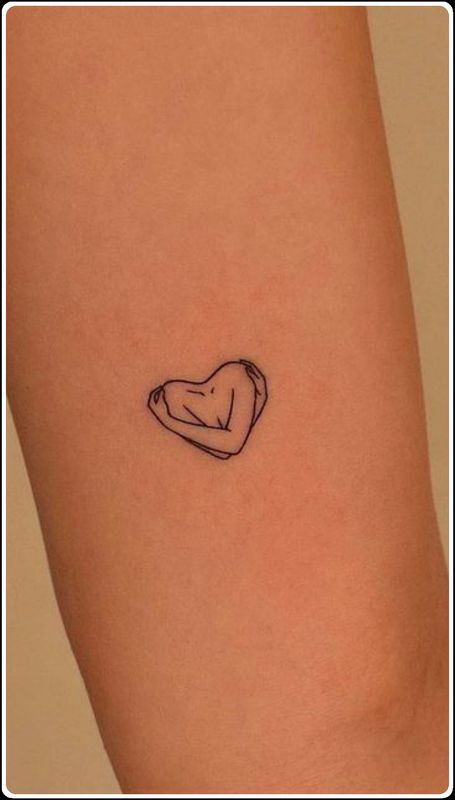 a small heart tattoo on the left side of the leg, with a dog's head in it