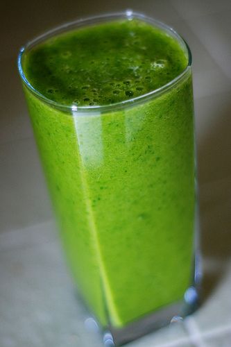 a green smoothie in a tall glass on a table