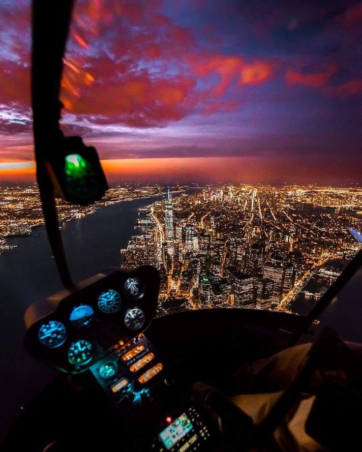 an aerial view of the city lights and buildings at night from inside a helicopter cockpit