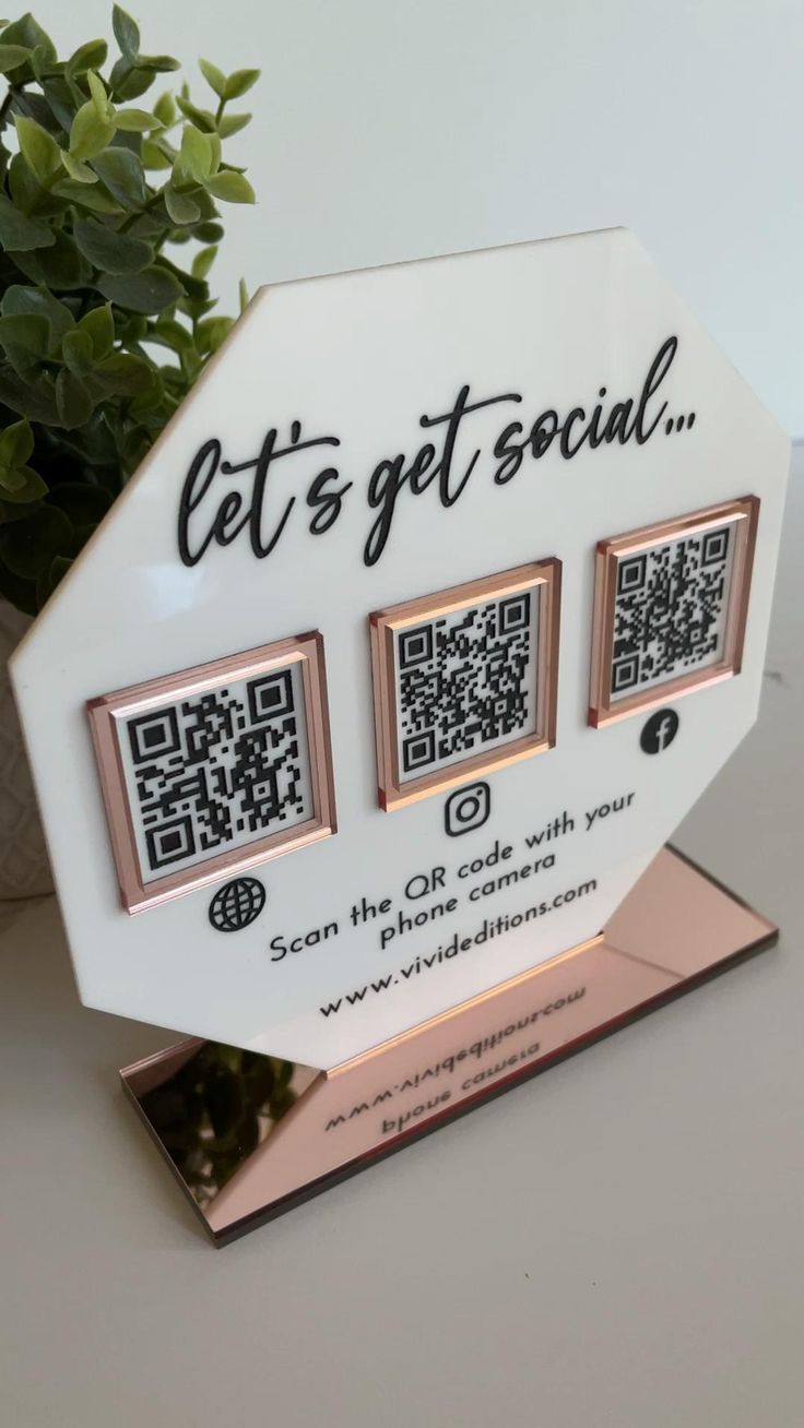 three qr code magnets sitting on top of a white table next to a potted plant