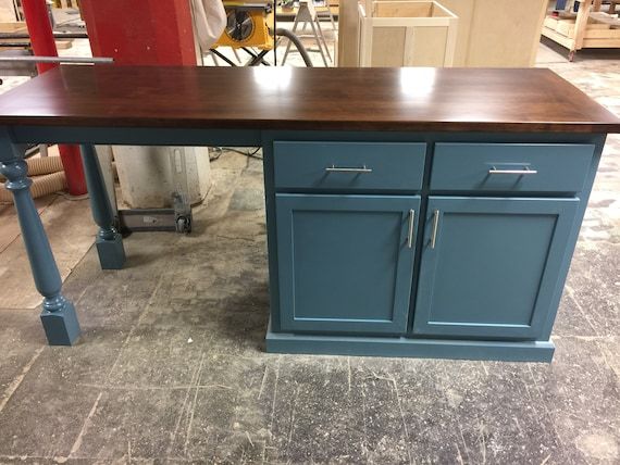 a kitchen island made out of wood with metal legs and drawers on the top, in a shop