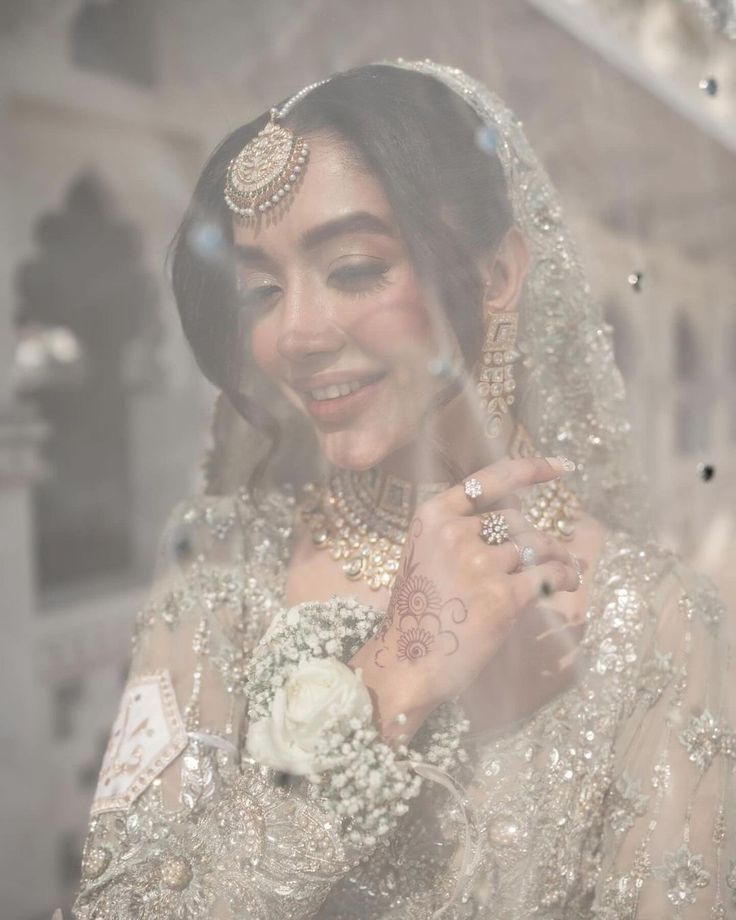 a woman in a bridal gown is smiling and posing for the camera with her hands on her chest