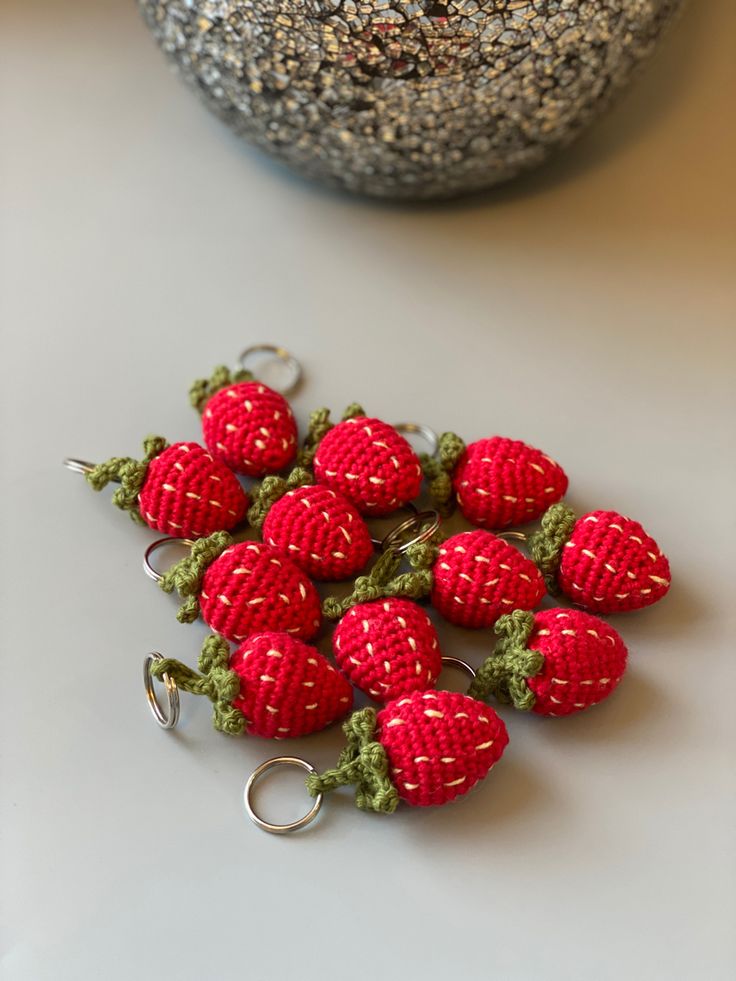 small crocheted strawberries sitting on top of a table next to a rock