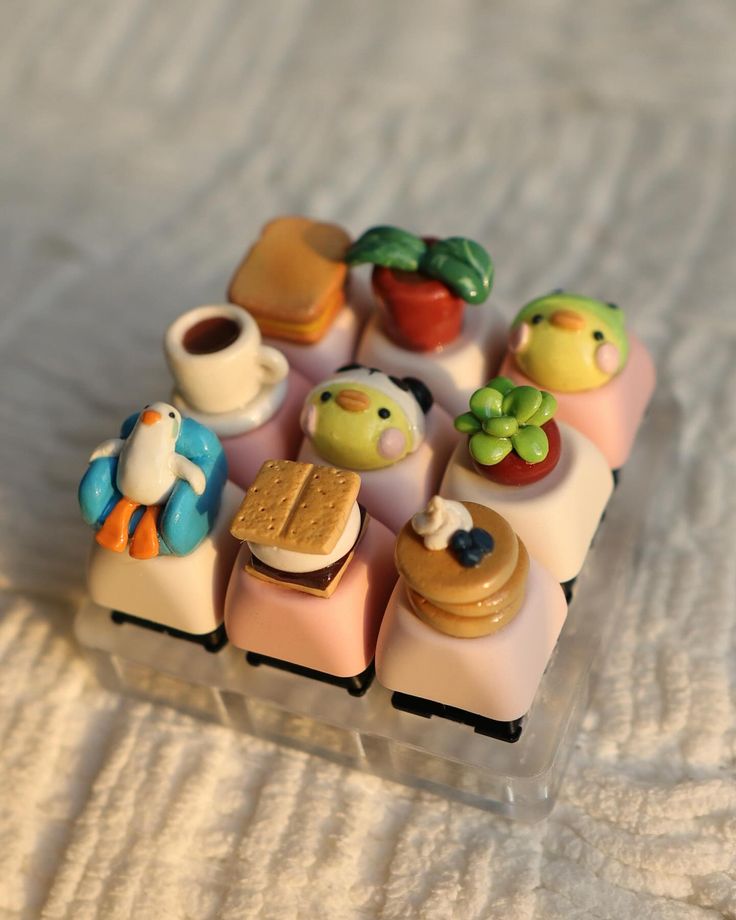 small toy food items sitting in a plastic container on a white sheet covered tablecloth