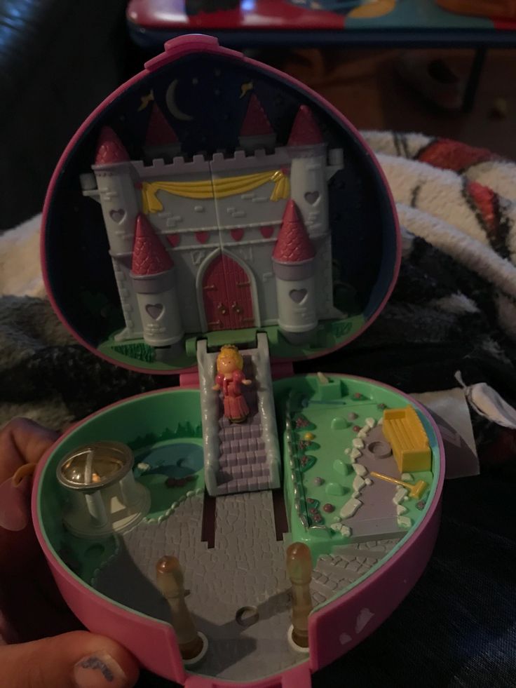 someone is holding a small toy castle in their hand and it's inside the box