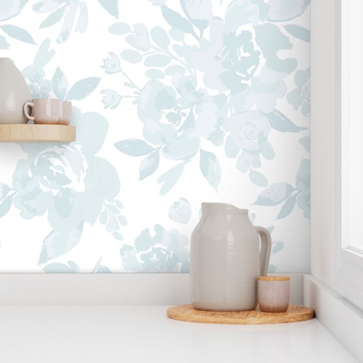 a white vase sitting on top of a counter next to a cup and saucer