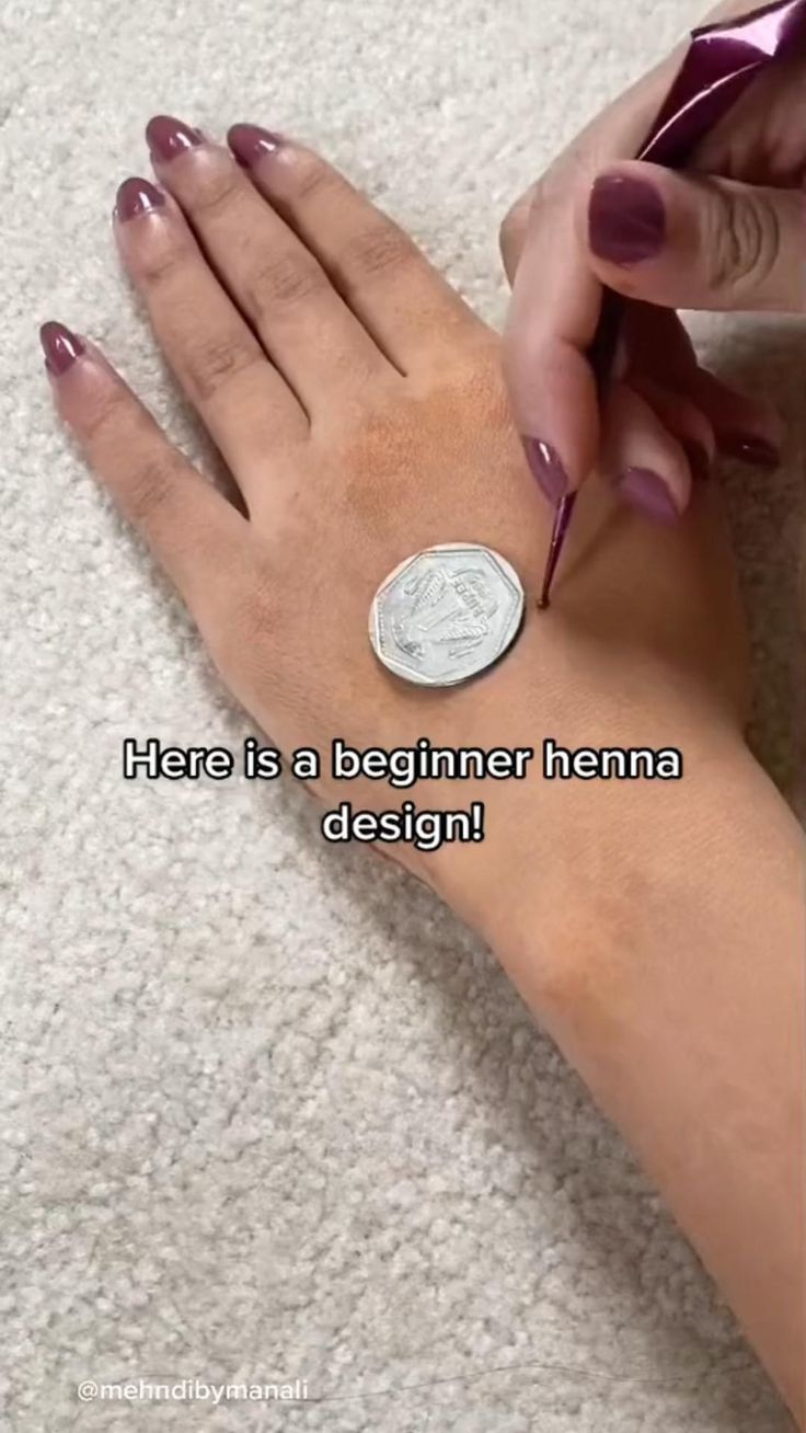 a woman is doing something on her arm with a coin in front of her and the words here is a beginner henna design