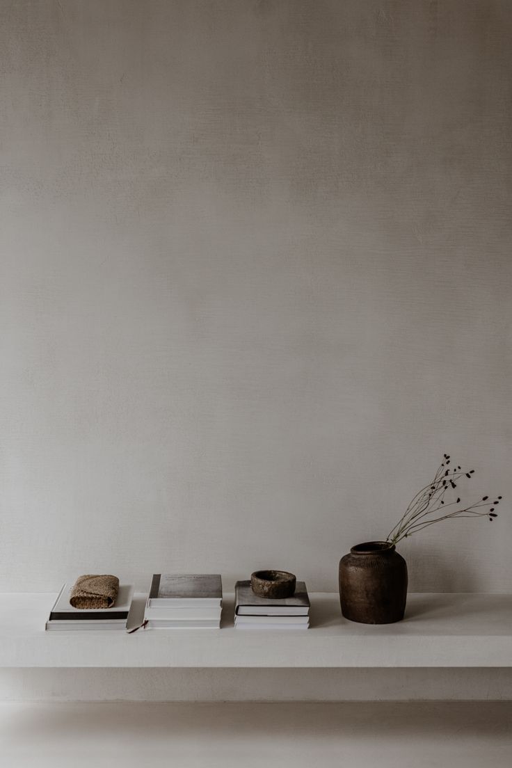 a white shelf with some books and a vase on it