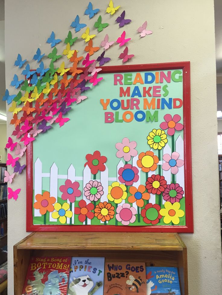 a book shelf filled with lots of books and butterflies on top of it, next to a sign that says reading makes your mind bloom