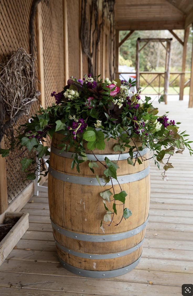 a wooden barrel with flowers in it sitting on a wood floor next to a building