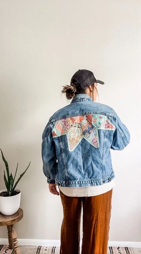 a woman standing in front of a wall wearing a jean jacket