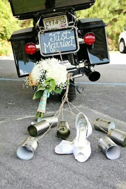 the wedding bouquet and shoes are tied to the back of a motorbike with just married written on it