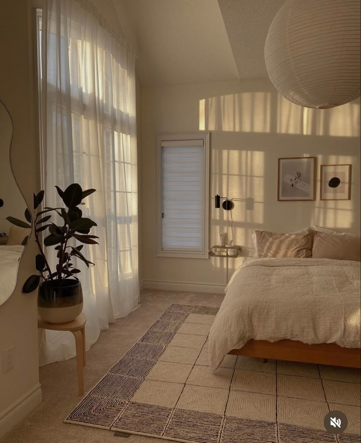 a bed room with a neatly made bed next to two windows and a potted plant