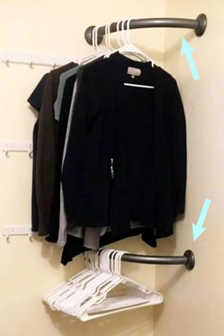 clothes hanging on the wall with an ironing board attached to it and two hangers holding clothing