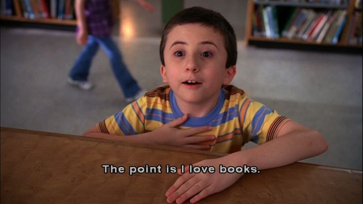 a young boy sitting at a table in front of a book shelf with the caption, the point is i love books