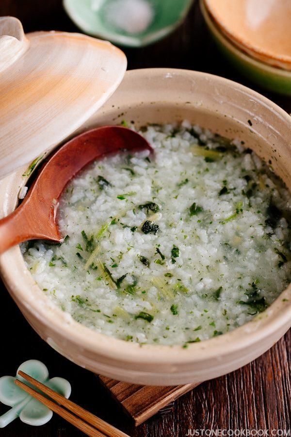 a wooden spoon sitting in a bowl filled with rice next to bowls and chopsticks