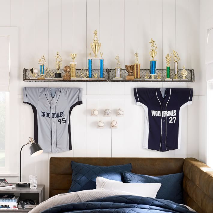 two sports jerseys hung on the wall above a bed with blue comforter and pillows