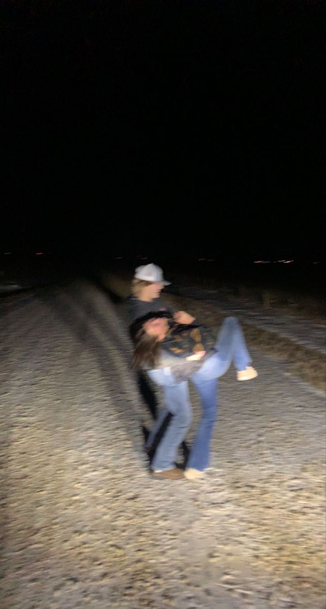 two people sitting on the side of a road at night