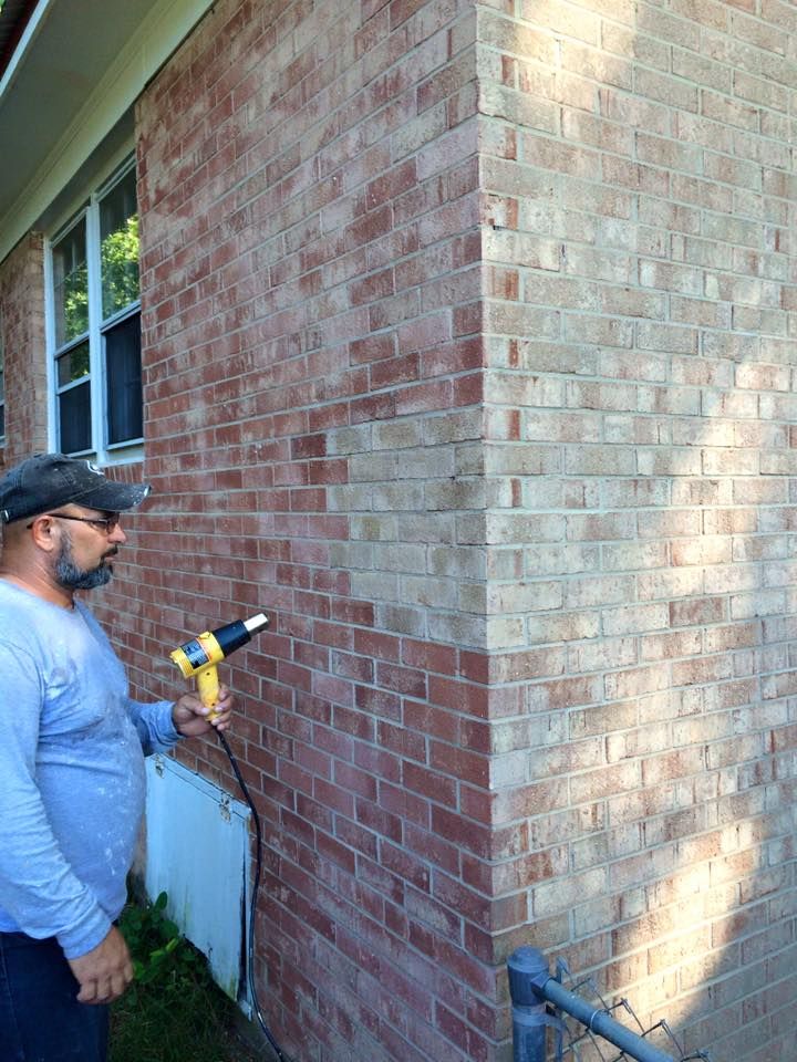 a man using a power drill to fix a brick wall in front of a house