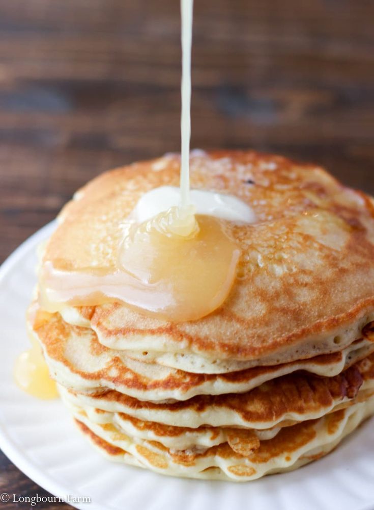 a stack of pancakes with syrup being poured on top