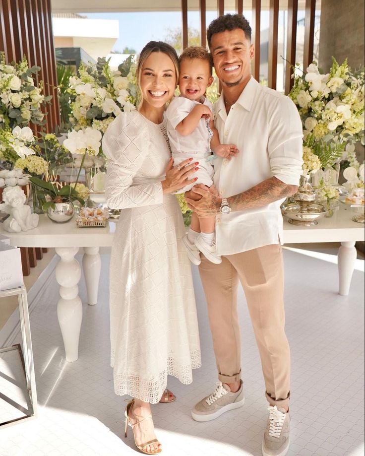 a man, woman and child standing in front of a table with flowers on it