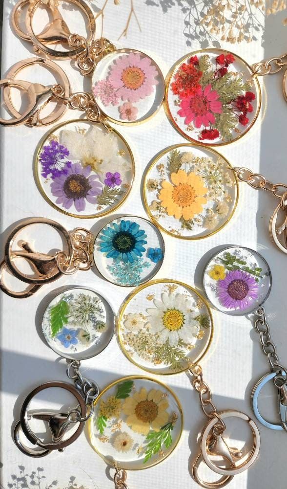 many different types of flowers are on display in the window sill with key chains attached to them